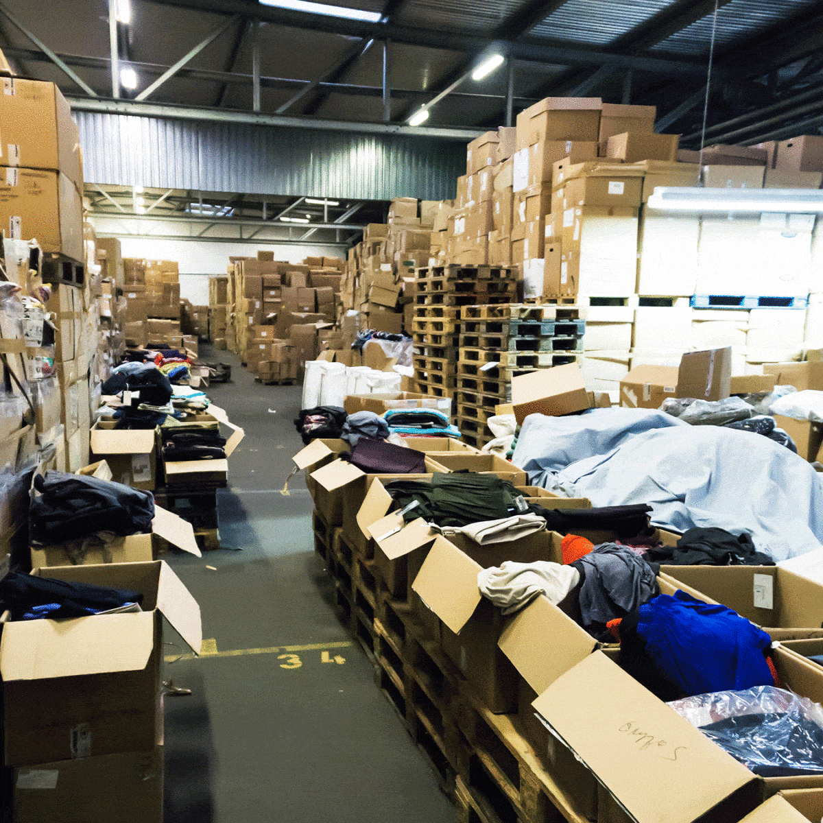 A warehouse containing boxes of clothes on shelves and on the floor