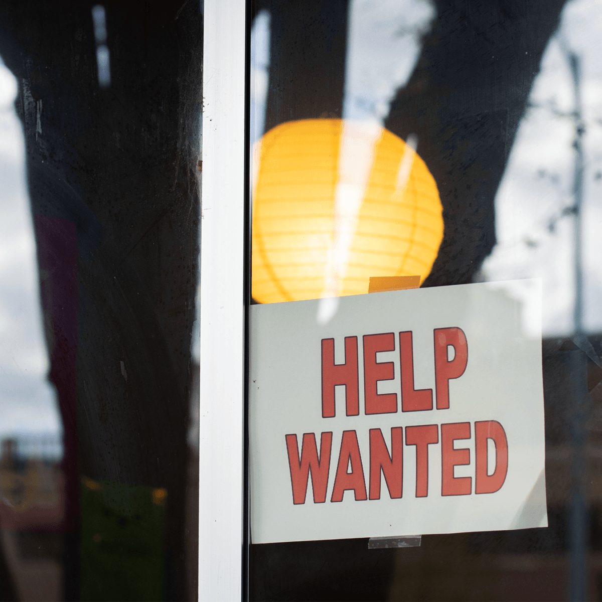 A 'help wanted' sign hangs in the window of a restaurant