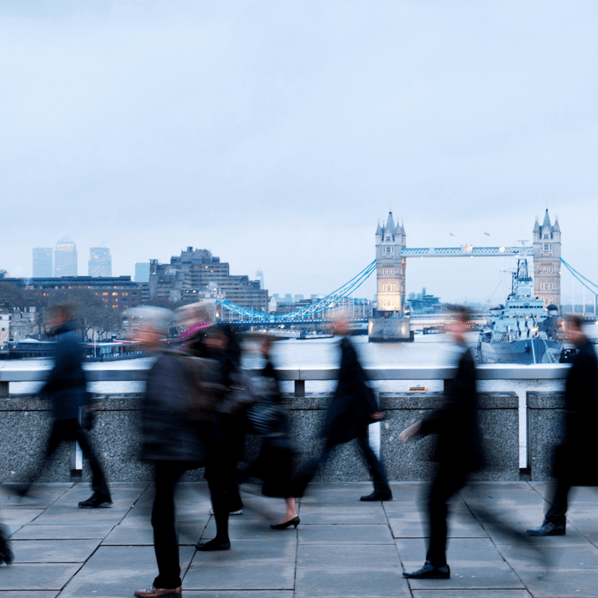Commuters walking across London Bridge, with Tower Bridge in the background